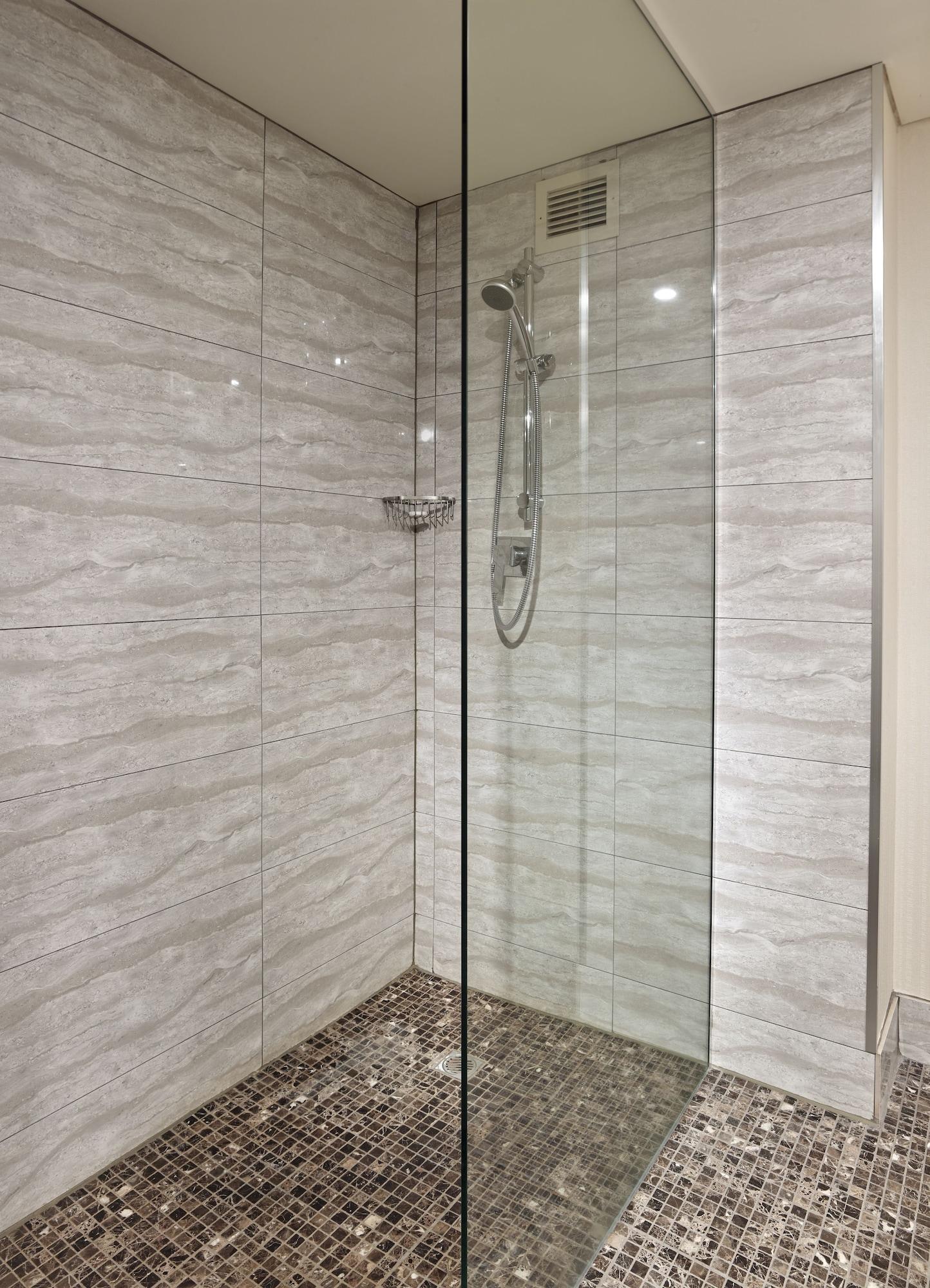 Hotel Stamford Grand Adelaide Glenelg Exterior foto The photo shows a modern shower enclosure with a transparent glass door. The interior features tiled walls in a light, marble-like pattern, creating a clean and sleek look. There is a showerhead mounted on the wall, and the floor appears to be tiled 