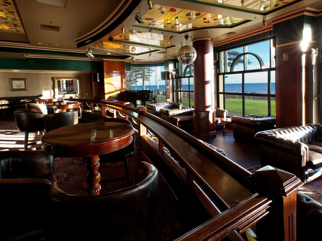 Hotel Stamford Grand Adelaide Glenelg Exterior foto The photo depicts a stylish and inviting interior of a lounge or bar. It features comfortable leather seating, wooden tables, and large windows that provide a view of the outdoors. The ceiling is adorned with decorative elements, and there’s a disco 
