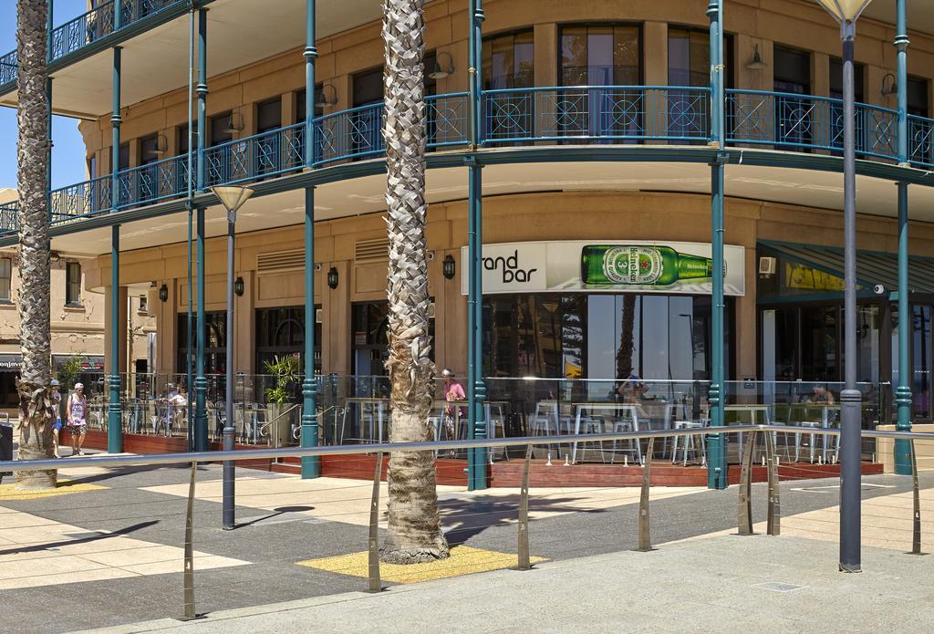 Hotel Stamford Grand Adelaide Glenelg Exterior foto The photo shows a corner of a building that houses a bar with the name "End Bar" prominently displayed. It's a multi-level structure with balconies featuring decorative railings. In front of the bar, there are tables and chairs, indicating a dining o