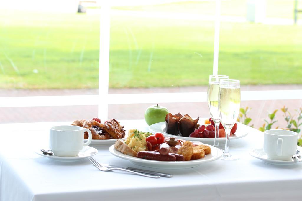 Hotel Stamford Grand Adelaide Glenelg Exterior foto The photo displays a beautifully arranged breakfast setup on a white tablecloth. In the center, there is a large white plate with a variety of foods, including eggs, sausage, and fresh fruit. Surrounding the plate are a few other food items, such as 